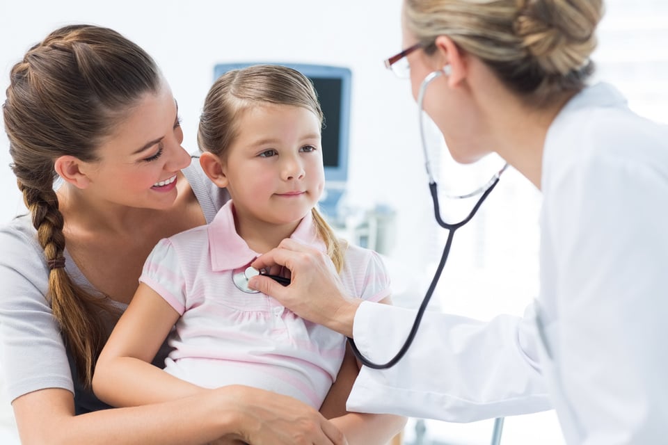 Mother with girl being examined by female pediatrician in clinic